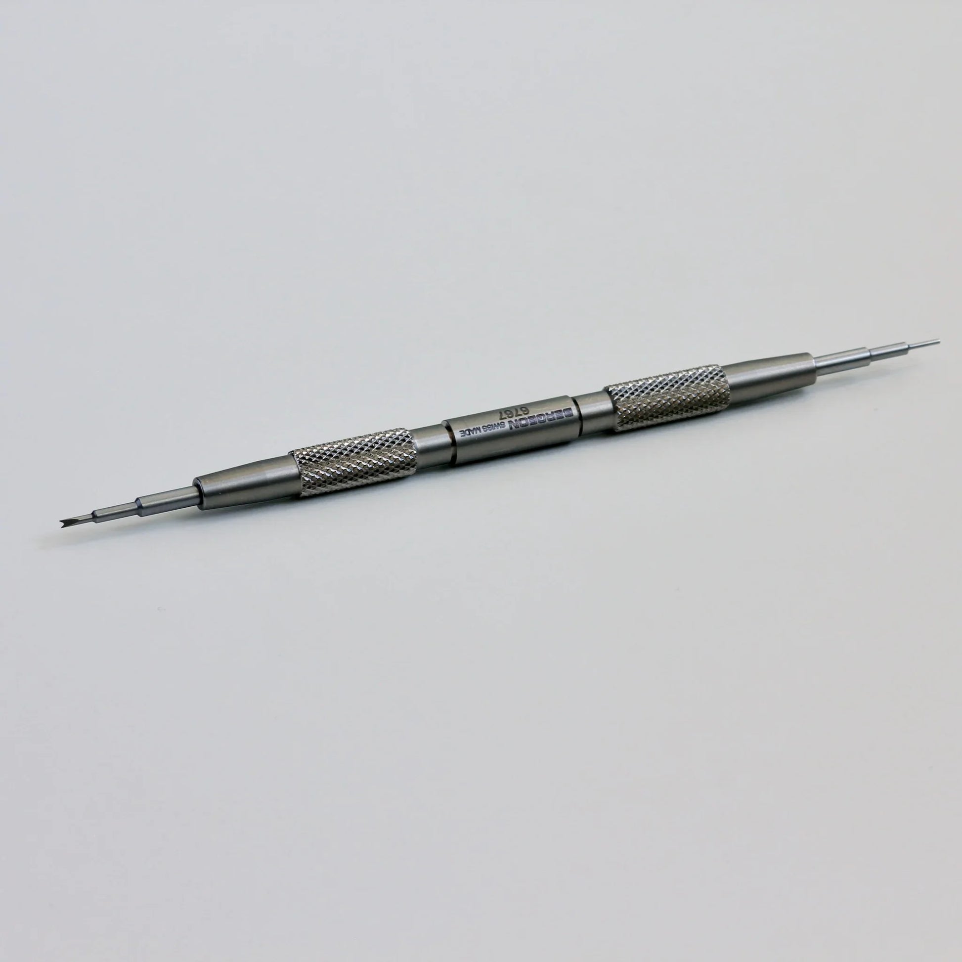 Double-ended stainless steel watch repair tool with textured grip on white background