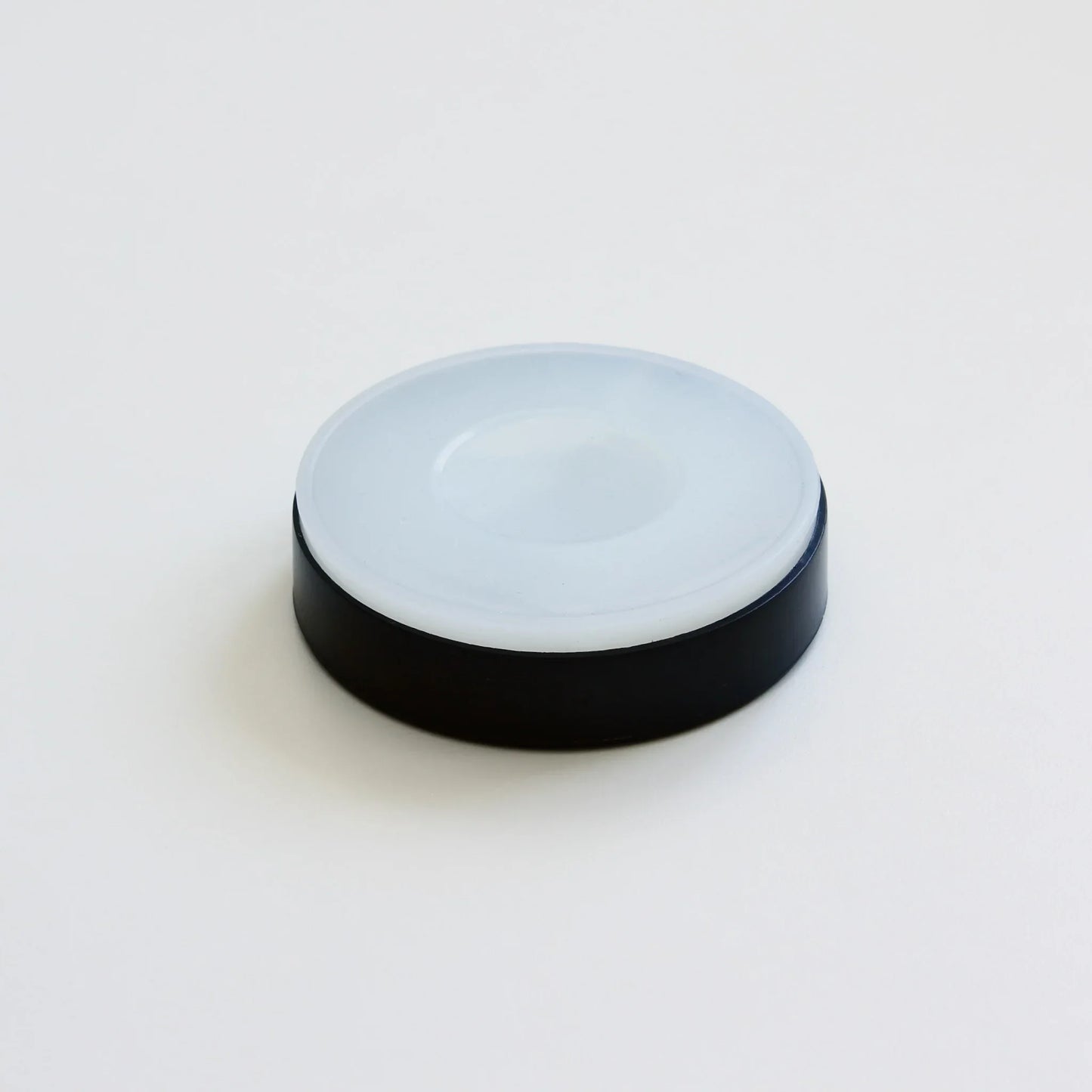 Round black and white plastic cap or lid on white background, repair supply accessory